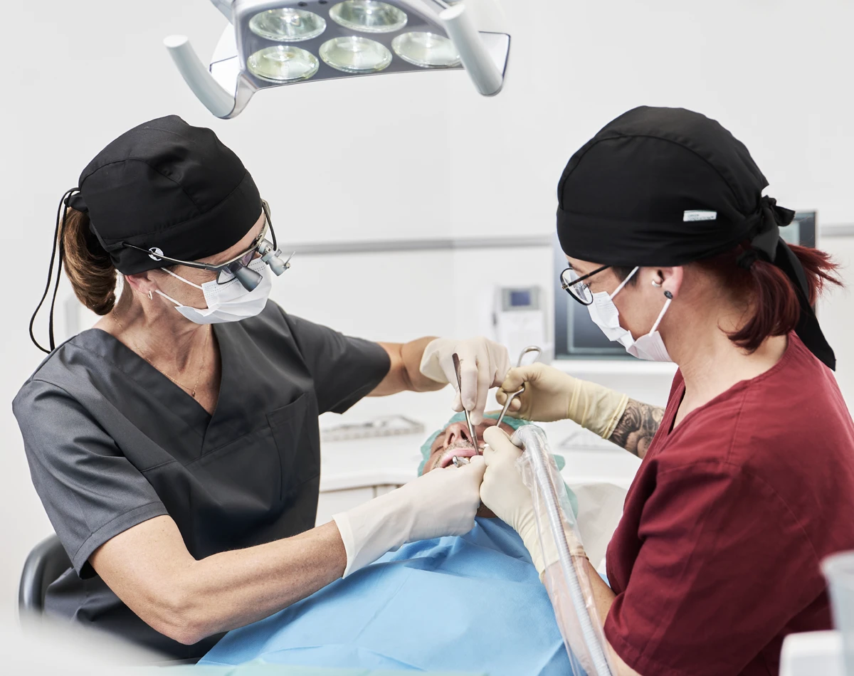 Zahnärztin Dr. Scheffler und Assistentin behandeln gemeinsam einen Patienten.